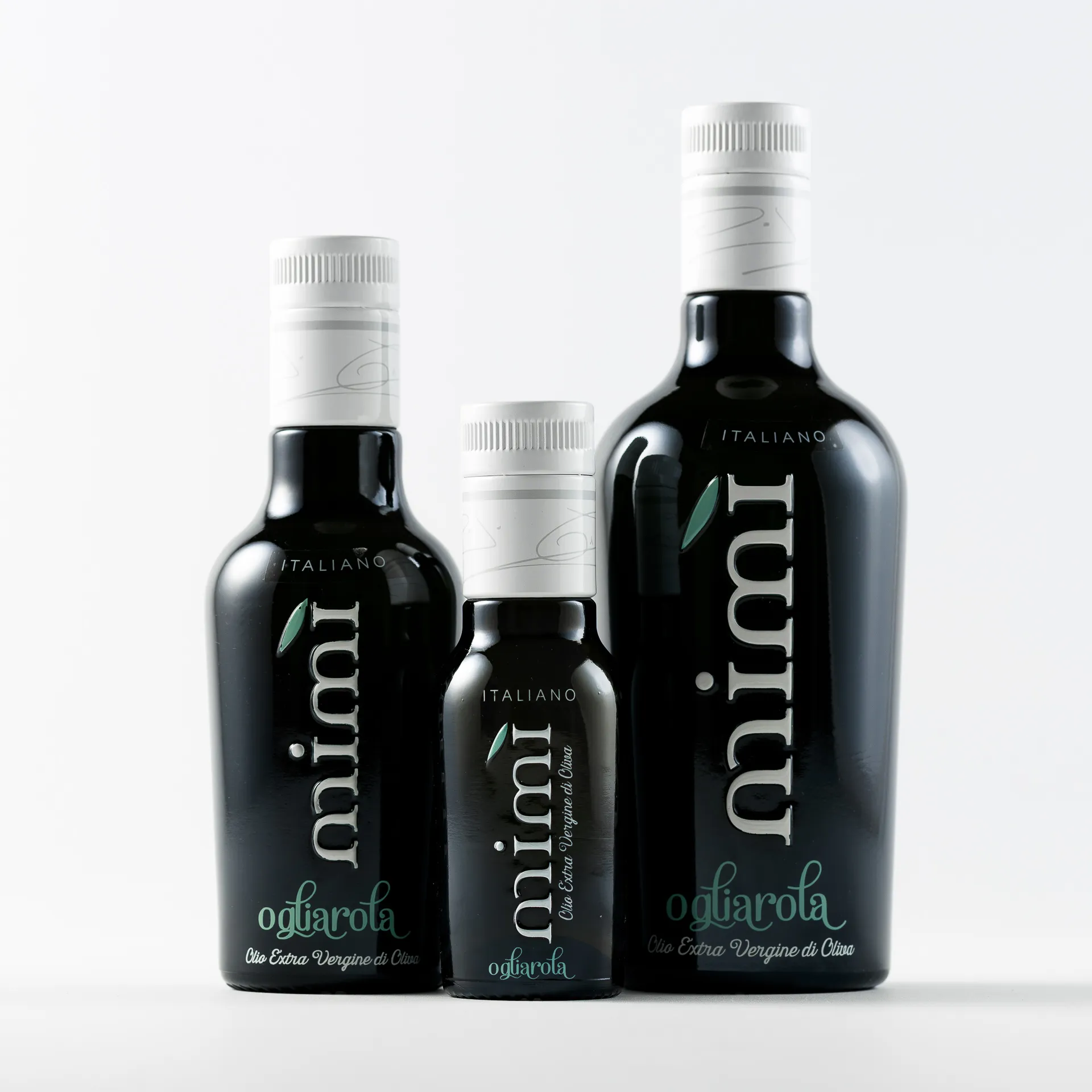 Three black bottles of Mimi Ogliarola Italian extra virgin olive oil in small, medium, and large sizes are arranged side by side on a white surface with a plain background.