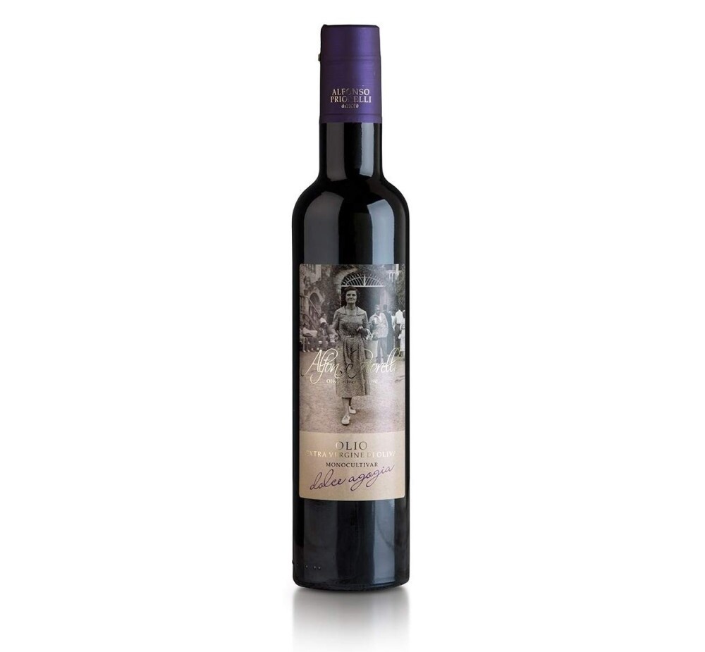 Una bottiglia alta di vetro scuro di olio extra vergine di oliva con tappo viola ed etichetta in stile vintage con una fotografia in bianco e nero.